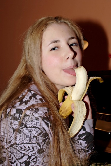 Young looking girl with long hair eats a banana before stripping to her socks 20679278