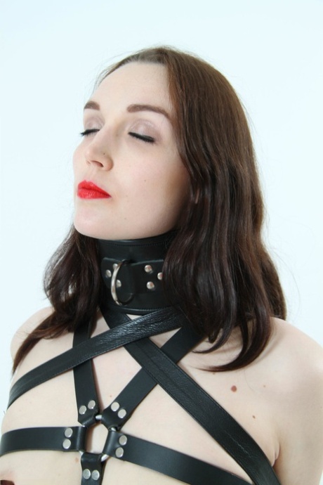 Beautiful girl models leather BDSM attire with her arms restrained behind her 58954747